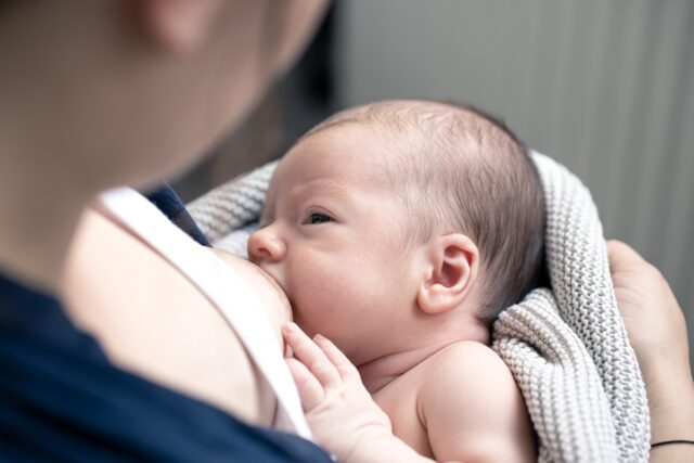 Portrait of a newborn baby boy drinking mother's breast milk.